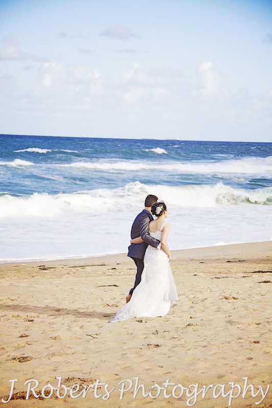 bride and groom walking along the beach - wedding photography sydney